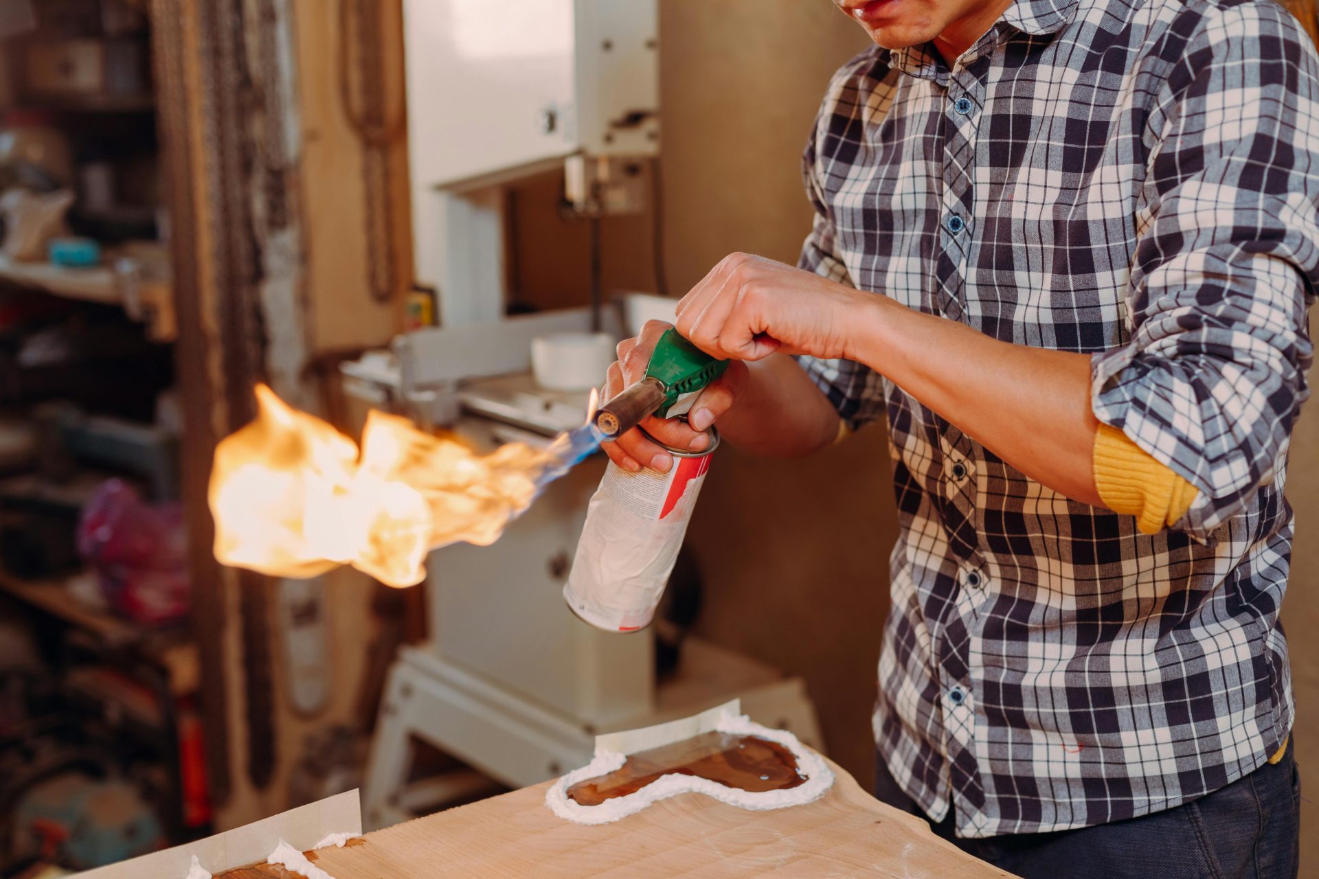 Closeup of an artisan using a blowtorch to work on epoxy resin in a workshop.