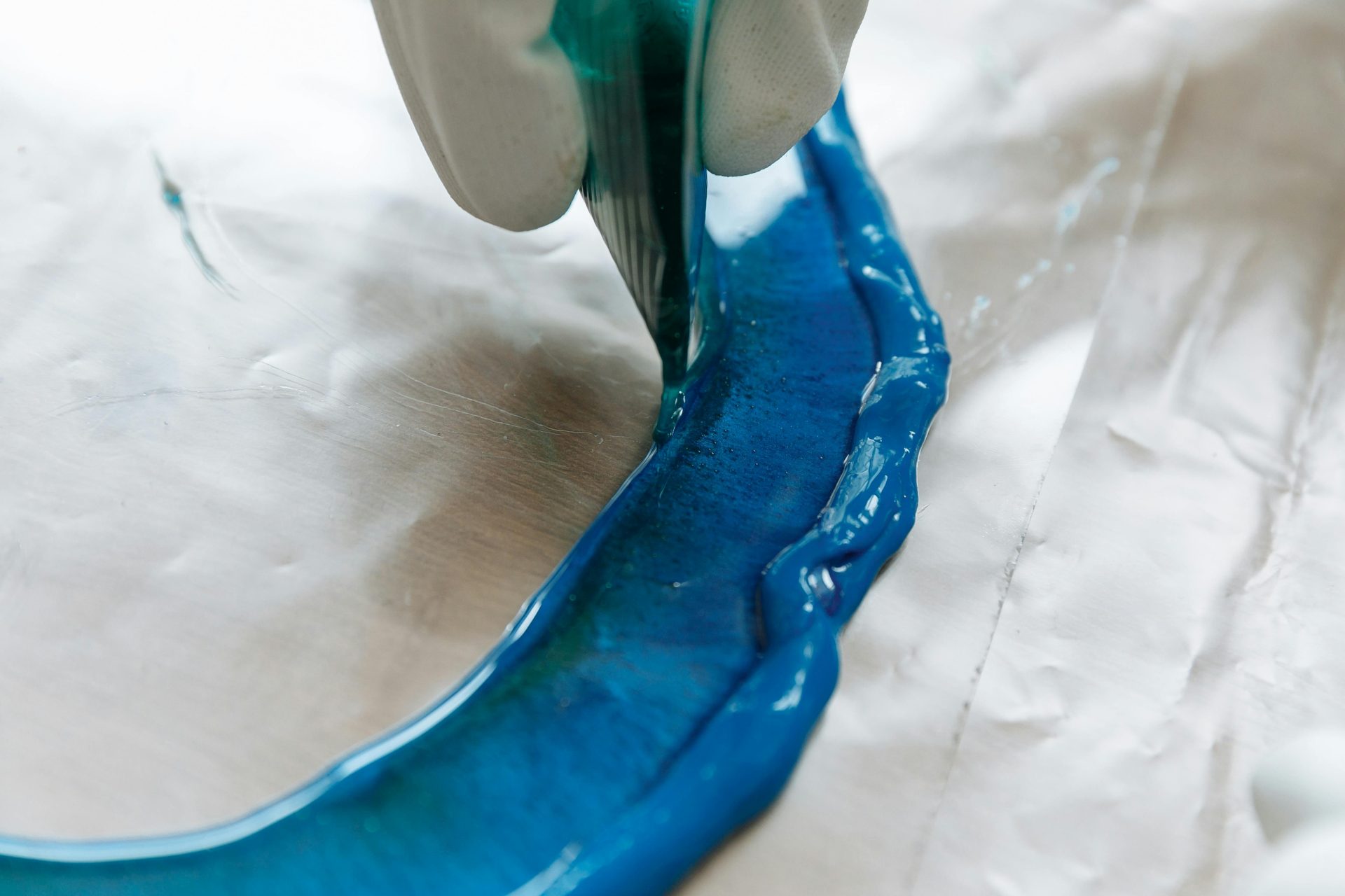 Detailed view of blue resin being poured in an art project, perfect for DIY crafts.